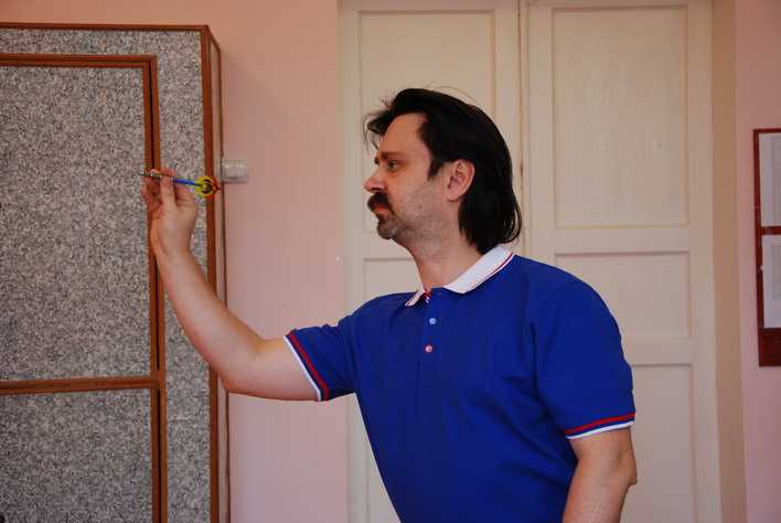 Алексей Баранов кидает дротики в помещении шахматного клуба ДЮСШ