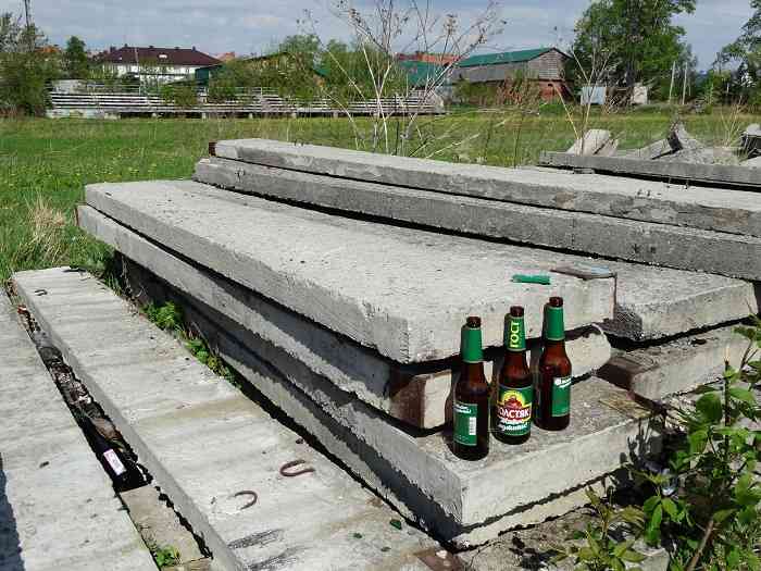 Бутылки на плитах, которые свалены на бывшем футбольном поле.