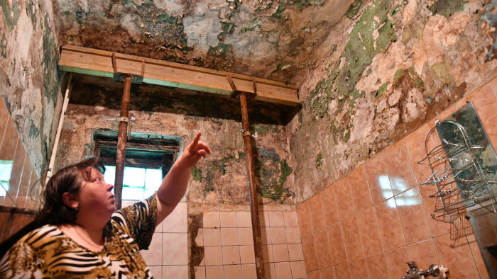 Старшая по дому Надежда Кальзова опасается, что в душевой может рухнуть потолок. Строители укрепили стену, но трещина, из-за которой останавливали работы в прошлом году, стала больше. Фото Владимира Коцюбы-Белых